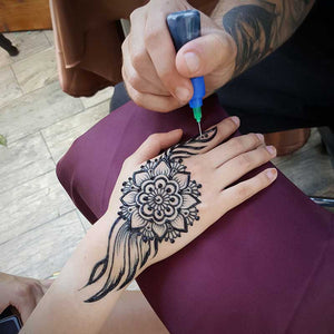 Design of henna - Henna artists doing traditional hand henna tattoo.