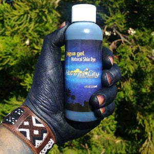 Jagua stained hand holding a 4 oz bottle of henna city jagua ink gel.